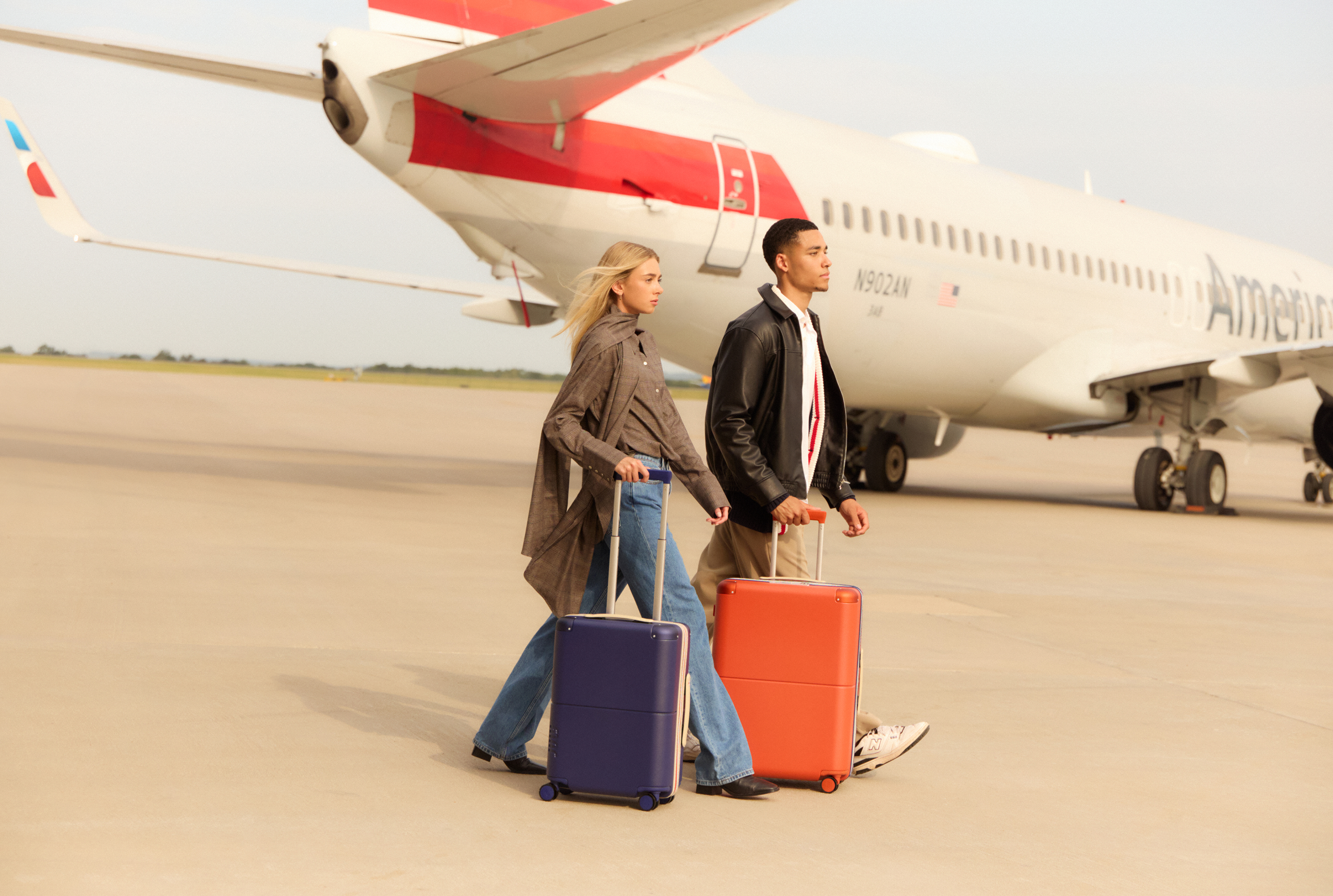 Two travellers crossing the apron with the collection, an American Airlines aircraft behind them