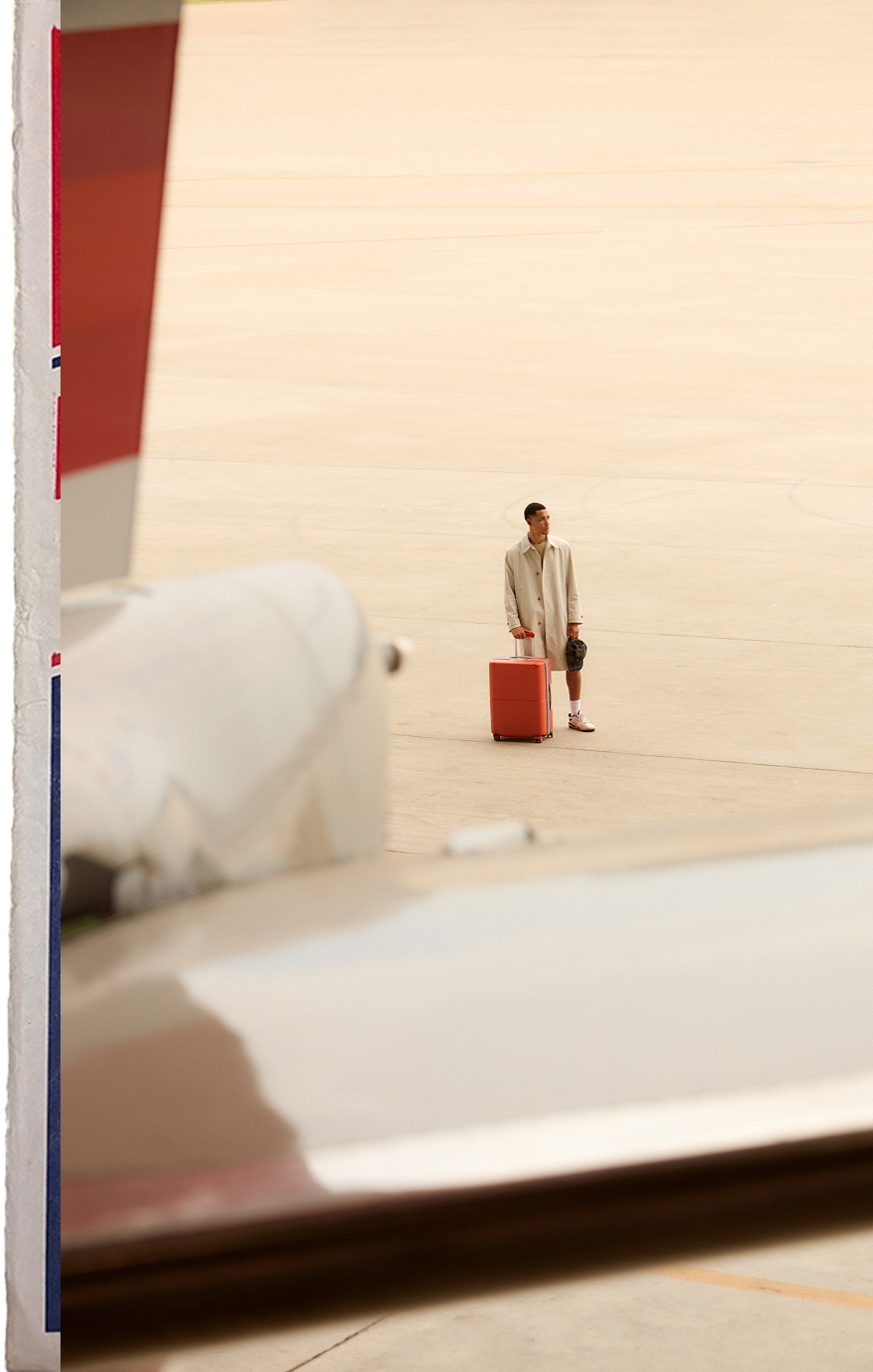 Traveller standing beside a red July suitcase