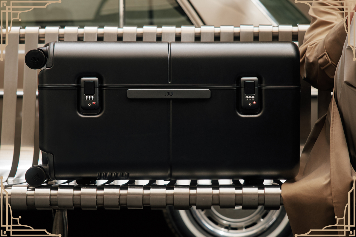 A black July Trunk resting on a bench showing its twin latch locks